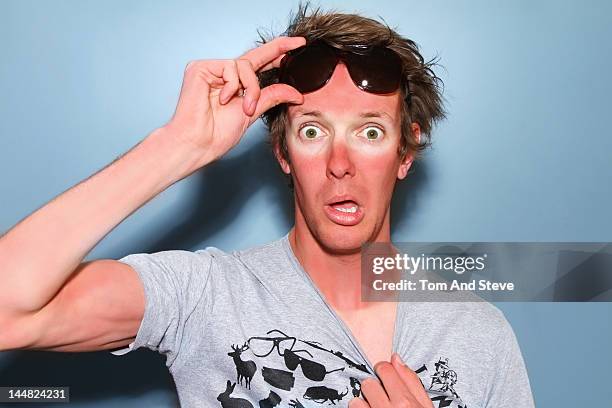 man raises his sunglasses in shock at his sunburn - careless stock pictures, royalty-free photos & images