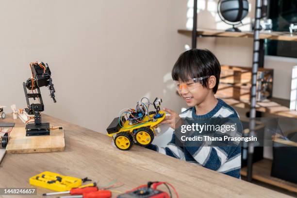 asian kid boy assembling the open-source hardware and software robot car homework project at home - open source development stock pictures, royalty-free photos & images