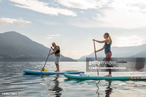 vater und tochter auf stand up paddle boards bei sonnenaufgang - paddelbrett stock-fotos und bilder