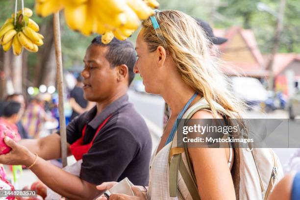 young woman buying fruits from a local market stall in thailand - market stall stock pictures, royalty-free photos & images