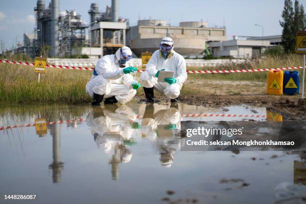 scientists wear protective clothing to analyze and collect samples of wastewater. - oil slick stock pictures, royalty-free photos & images