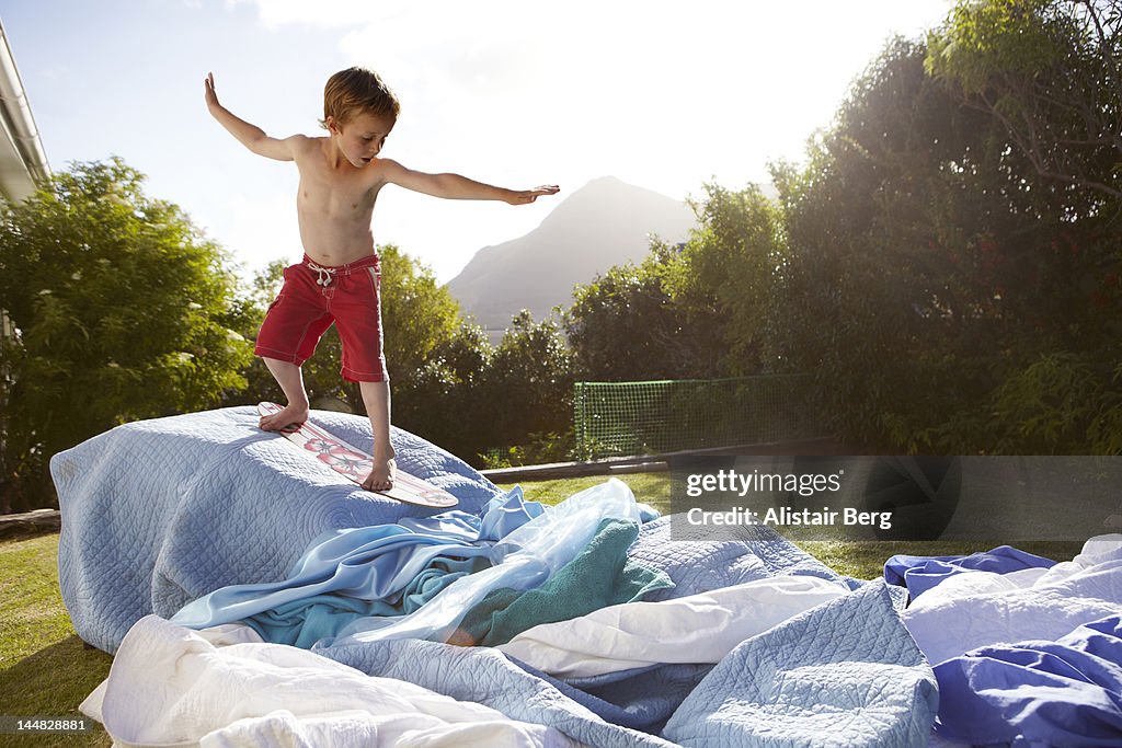 Boy pretending to be a surfer in a suburban garden