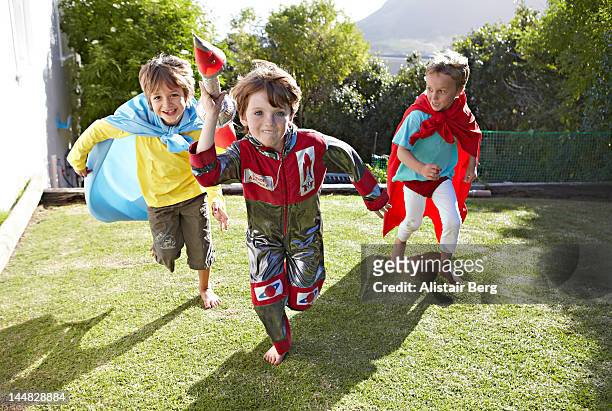 boys playing together in a garden - running fancy dress stock-fotos und bilder