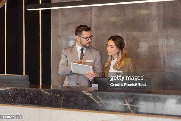 recepcionistas de hotel usando tableta digital - sala de espera edificio público fotografías e imágenes de stock