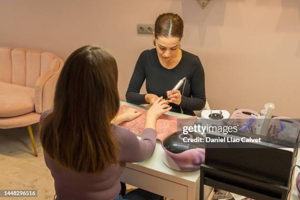 maestra de manicura utilizando una lima de uñas eléctrica para limpiar la uña en el salón de belleza. - limpiar stock pictures, royalty-free photos & images