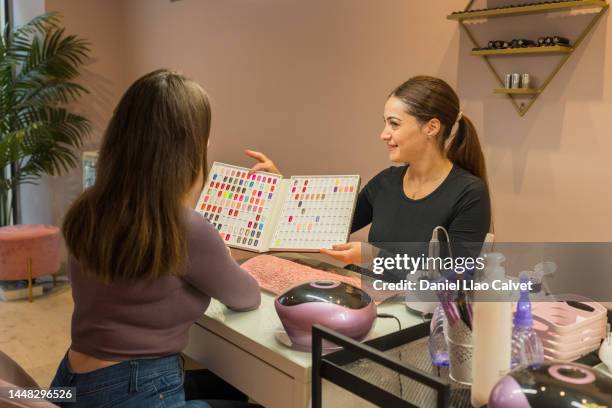 esteticista enseñando el muestrario de colores para el esmalte de las uñas - esmalte de uñas stock pictures, royalty-free photos & images