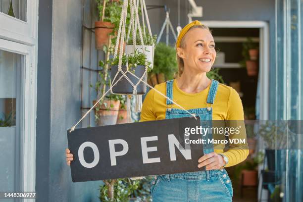 small business, owner and plant shop sign with friendly smile of girl at door entrance of nursery. welcome signboard of a sustainable business owner woman at garden shop in australia. - small placard stock pictures, royalty-free photos & images