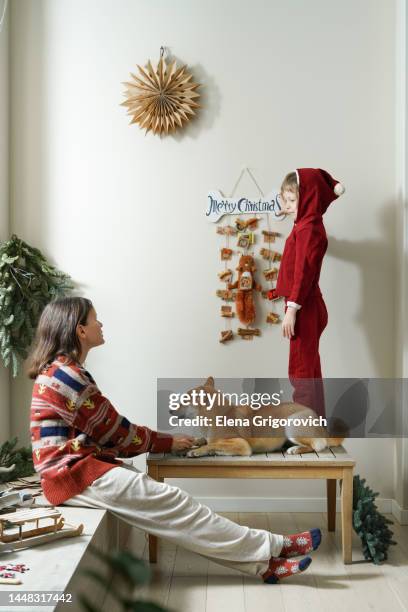 nuclear family making christmas decor in brightly room with hanging diy advent calendar for dogs - child with advent calendar 個照片及圖片檔