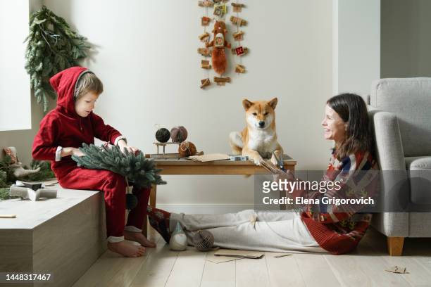 nuclear family making christmas decor in brightly room with hanging diy advent calendar for dogs - diy craft stock pictures, royalty-free photos & images