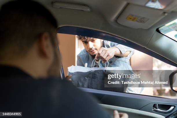 young man picking up a parcel in a drive through. - drive through stock-fotos und bilder