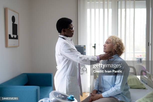 african american doctor having a medical exam with her patient in examination room. - throat exam 個照片及圖片檔