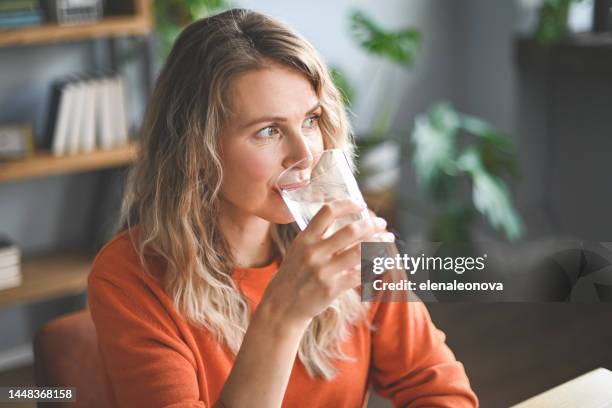 mujer adulta madura bebiendo agua de un vaso - vaso de agua fotografías e imágenes de stock