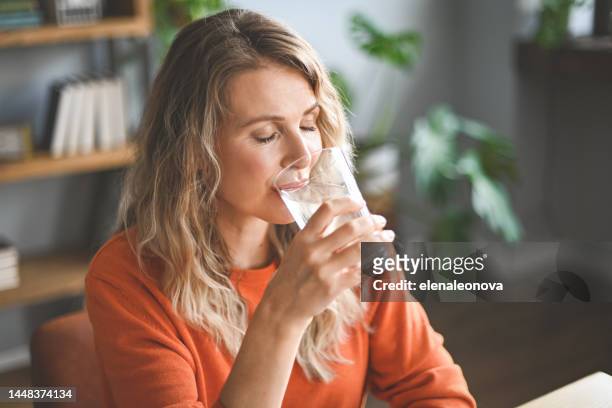 mujer adulta madura bebiendo agua de un vaso - agua dulce fotografías e imágenes de stock