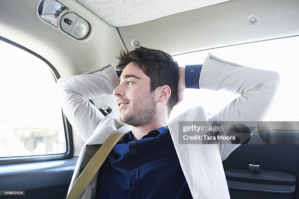 Business man relaxing in taxi and smiling