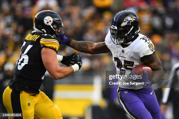 Gus Edwards of the Baltimore Ravens runs with the ball as Alex Highsmith of the Pittsburgh Steelers attempts the tackle during the third quarter of...