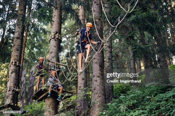 teenage kids having fun in ropes course adventure park - obstacle course stock pictures, royalty-free photos & images