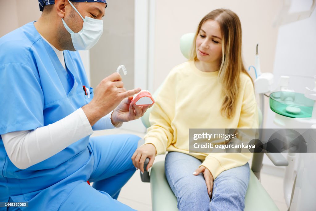 Dental invisible braces or silicone trainer in the hands of a young smiling women. Orthodontic concept - Invisalign