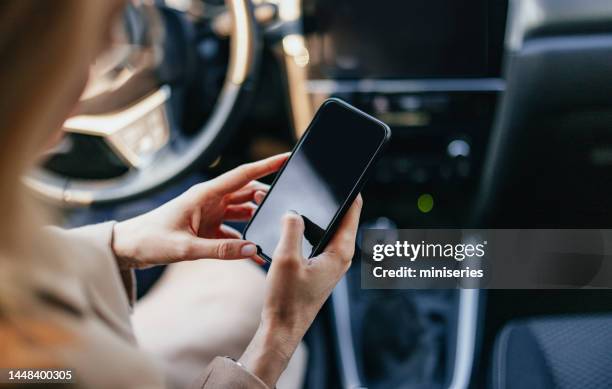 close up photo of woman hands using a mobile phone in the car - mobile app car stock pictures, royalty-free photos & images