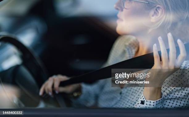 nahaufnahme foto von frauenhänden, die den sicherheitsgurt im auto anschnallen - sicherheitsgurt stock-fotos und bilder