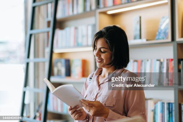 mujer leyendo un libro en la biblioteca - knowledge is power fotografías e imágenes de stock