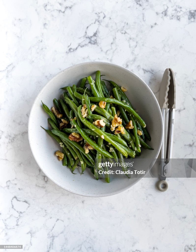 Bowl of green beans salad on white, marble background