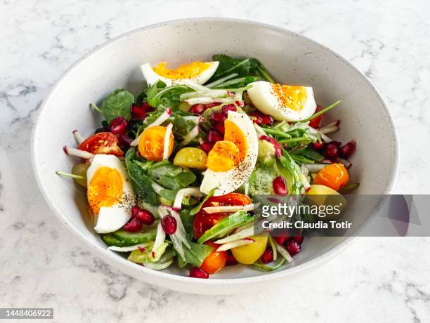 bowl of fresh salad with pomegranate seeds and boiled eggs on white background - salad bowl stock pictures, royalty-free photos & images