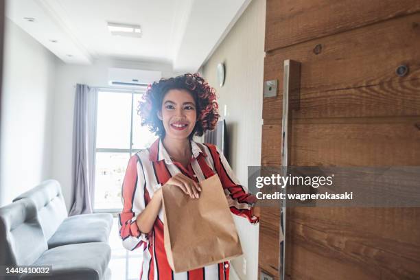 young pregnant woman receiving a takeaway food delivery at her doorstep - pregnant women greeting stockfoto's en -beelden