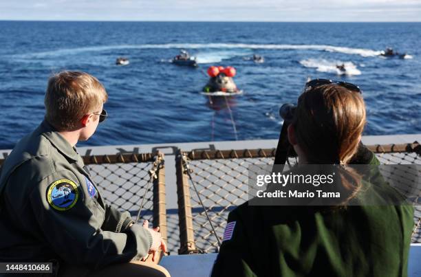 Recovery team members watch as NASA's Orion Capsule is drawn to the well deck of the U.S.S. Portland after it splashed down following a successful...