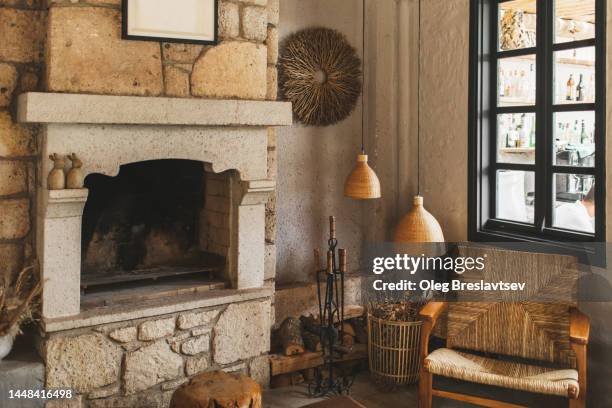 cozy nook at home with stone fireplace. lot of natural wicker wooden furniture - nook architecture stockfoto's en -beelden