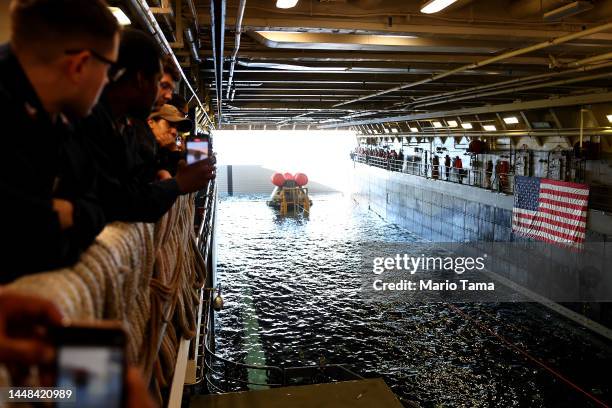 Crew members gather after NASA's Orion Capsule was brought into the well deck of the U.S.S. Portland, after it splashed down following a successful...