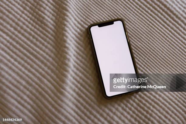 smart phone with blank screen on white bedspread - phone still life stock pictures, royalty-free photos & images