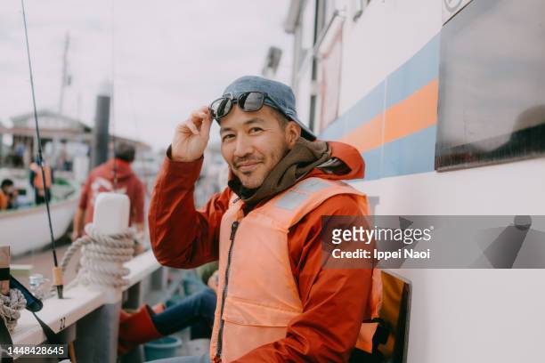 happy man on winter fishing trip by boat, tokyo bay - asian fishing boat stock-fotos und bilder