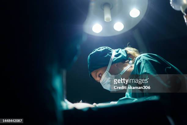 teamwork and cooperation three surgeons performing operating on a patient in the hospital's operating room - operating imagens e fotografias de stock