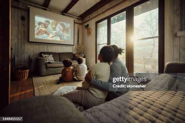 vista trasera de una familia negra relajada viendo una película en casa. - cinema screen fotografías e imágenes de stock