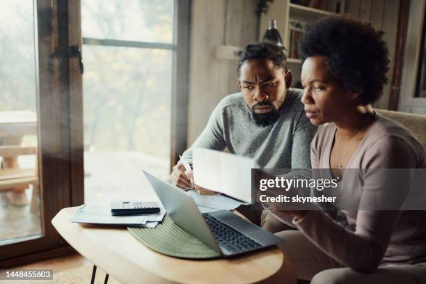 casal negro pagando suas contas em um computador em casa. - mortgage loan - fotografias e filmes do acervo