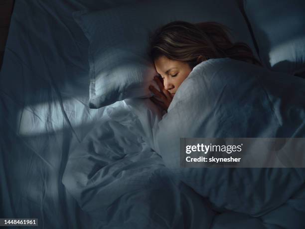 vista superior de una mujer relajada durmiendo en la cama por la noche. - soñar despierto fotografías e imágenes de stock