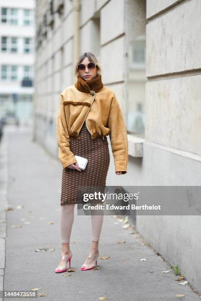 Emy Venturini wears beige circle sunglasses, gold large earrings, a yellow suede and brown sheep borders cropped / zipper aviator jacket, a brown...
