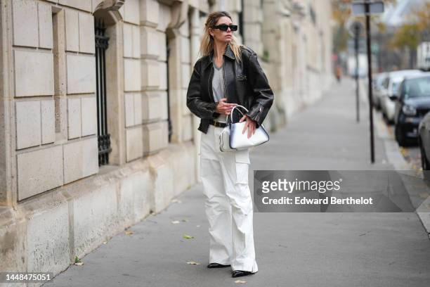 Natalia Verza wears black square sunglasses from Prada, silver earrings, a gray checkered jacquard print pattern V-neck / wool pullover, a black...