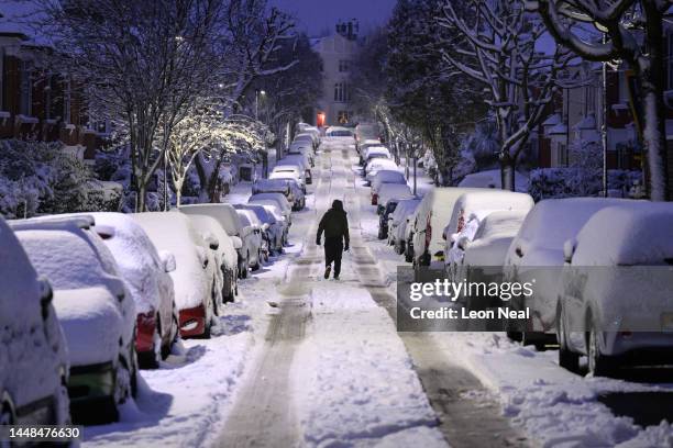 Man walks up a snow-covered road on December 12, 2022 in London, England. Snow and ice disrupted rail travel and closed schools in parts of southeast...