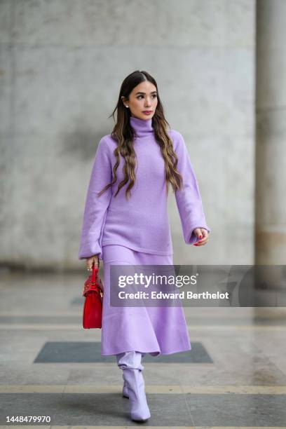 Heart Evangelista wears diamonds earrings, a pale purple / lilas wool turtleneck pullover, a matching pale purple / lilas wool long skirt, a red...