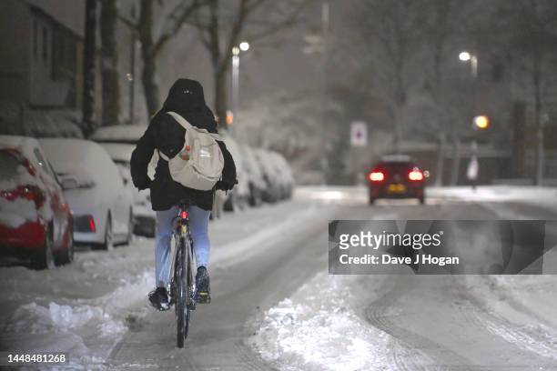 Cyclist rides along a snow covered street in Muswell Hill on December 12, 2022 in London, England. Snow and ice disrupted rail travel and closed...