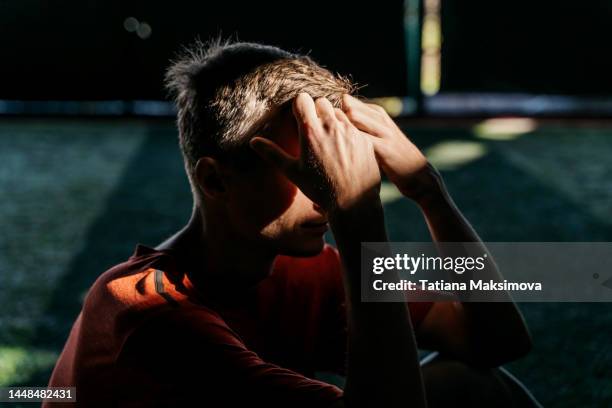 mid adult man in sunbeam in dark. depression concept. - headache stock-fotos und bilder