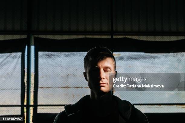 mid adult man in sunbeam in dark. depression concept. - bipolar stock-fotos und bilder