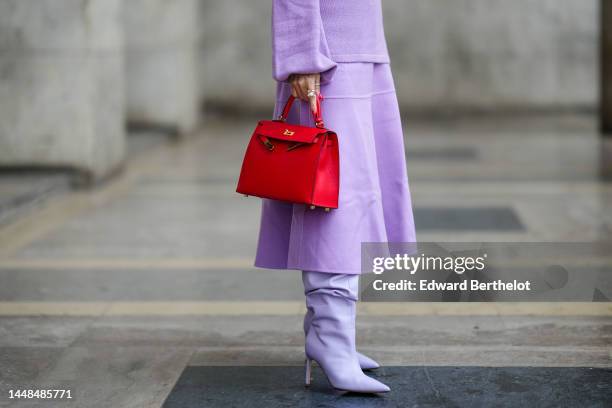 Heart Evangelista wears a pale purple / lilas wool turtleneck pullover, a matching pale purple / lilas wool long skirt, a red shiny leather Kelly...