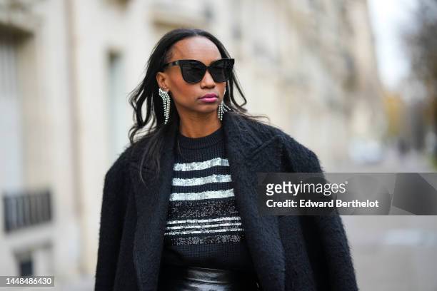 Emilie Joseph wears black sunglasses, a black wool with embroidered silver sequined striped print pattern pullover, silver rhinestones fringed...