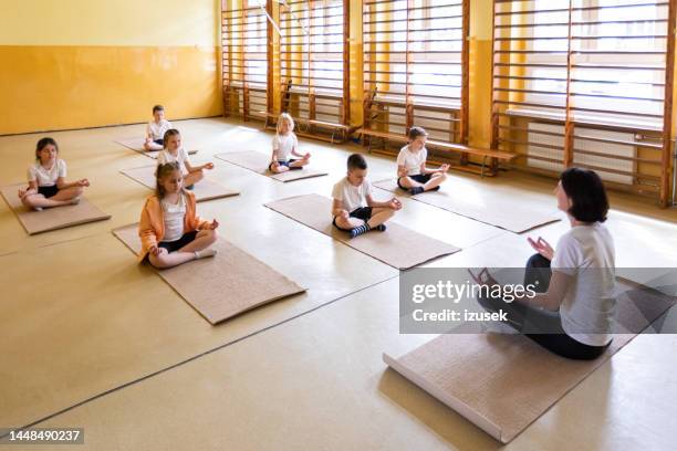 school children practicing yoga with teacher - school kids stock pictures, royalty-free photos & images