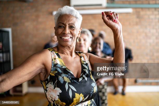 portrait of a senior woman dancing with her friends on a dance hall - zumba fitness stockfoto's en -beelden