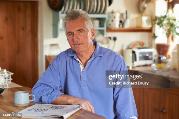 portrait of a senior man doing a crossword puzzle - house puzzle stock pictures, royalty-free photos & images