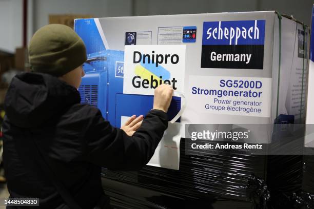 Member of the organisation adds a location sticker on the boxes of electric generators prior they will load onto a truck bound for Ukraine at a local...