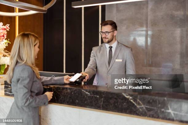 hotelrezeptionistin nimmt kontaktloses bezahlen entgegen - reception stock-fotos und bilder